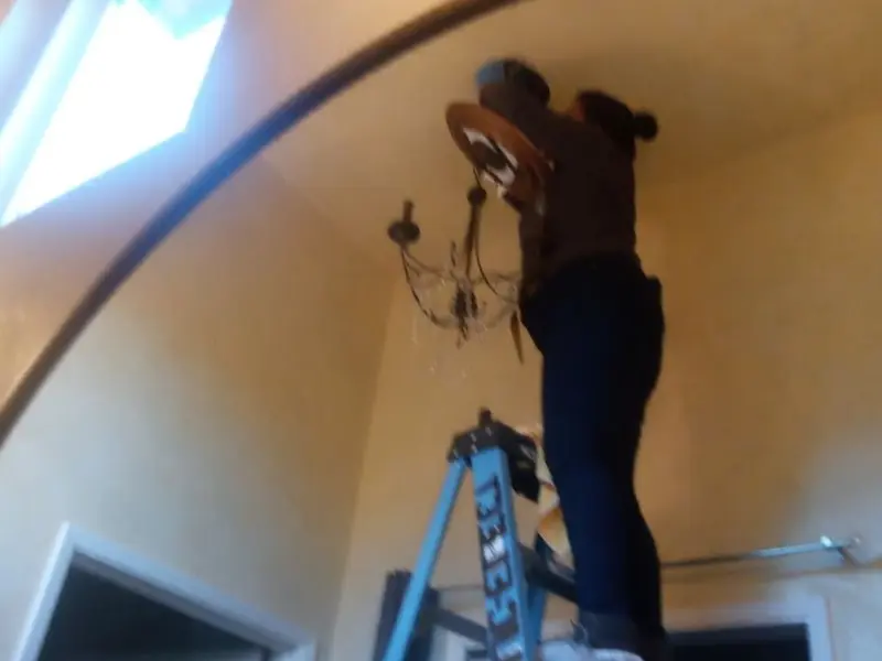 Electrician installing a chandelier in a Silver Lakes residence